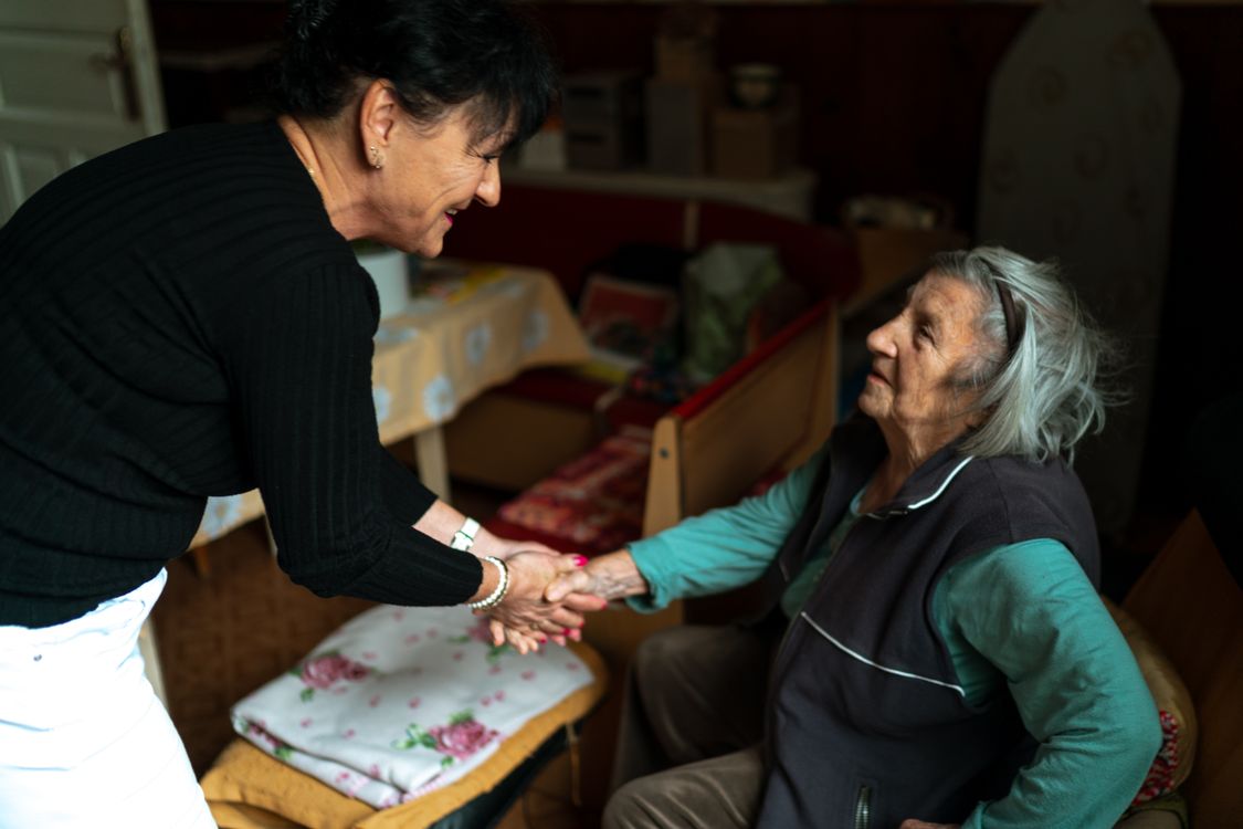 Care worker warmly greeting a senior woman at home